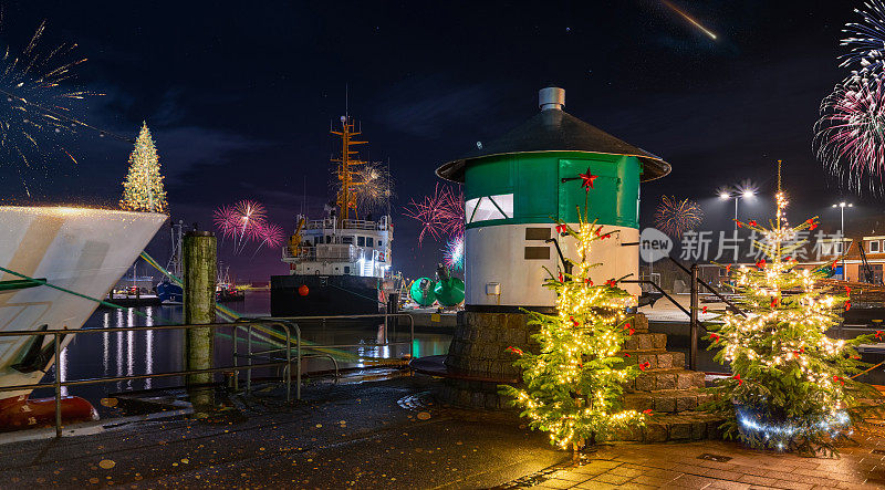 在德国北海海岸的b<s:1>苏姆渔港，绿色的码头灯光、圣诞树和烟花。除夕夜的浪漫气氛在夜晚的<s:1>萨姆燃放烟花。